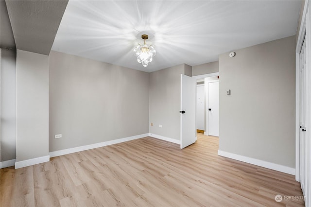 empty room with a notable chandelier and light hardwood / wood-style flooring