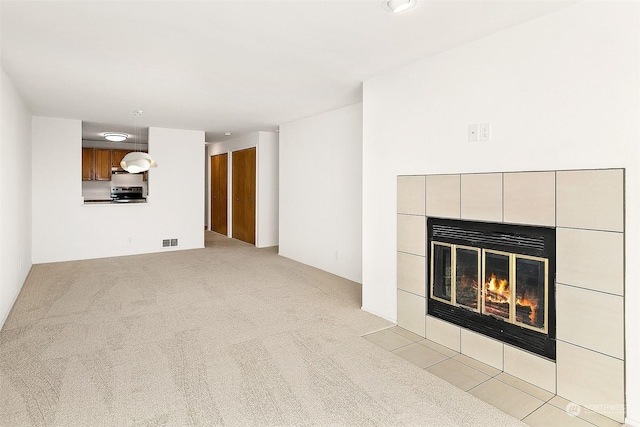 unfurnished living room with light carpet and a tile fireplace