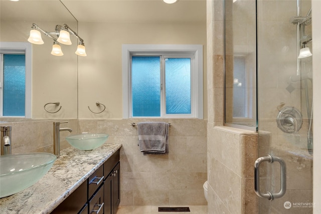 bathroom featuring vanity, a shower with shower door, and tile walls