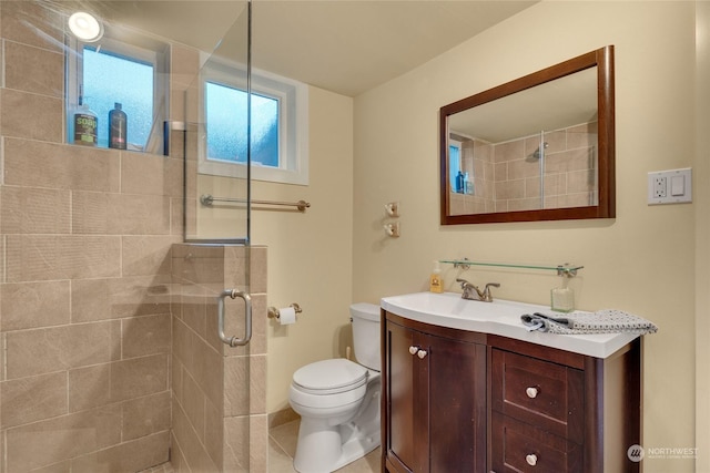 bathroom featuring toilet, vanity, and a shower with shower door