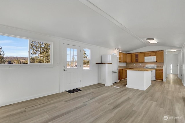 kitchen with lofted ceiling, white appliances, a center island, and light wood-type flooring