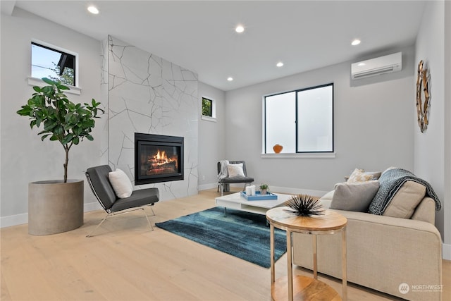 living room with wood-type flooring, a wall unit AC, and a premium fireplace