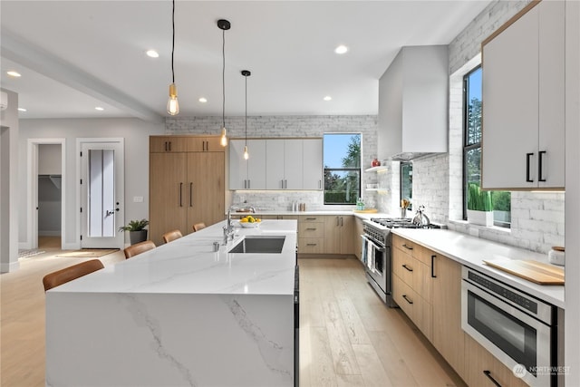 kitchen featuring appliances with stainless steel finishes, pendant lighting, white cabinetry, an island with sink, and sink