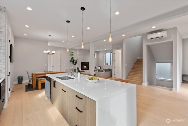 kitchen with a large island, sink, hanging light fixtures, a wall unit AC, and a large fireplace