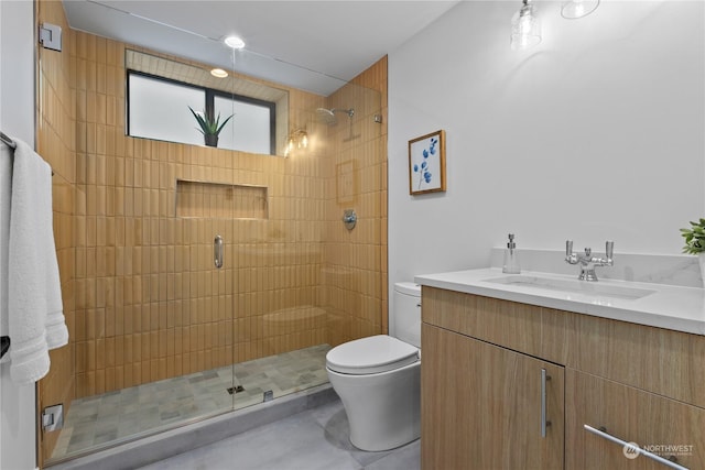 bathroom with vanity, a shower with door, and toilet