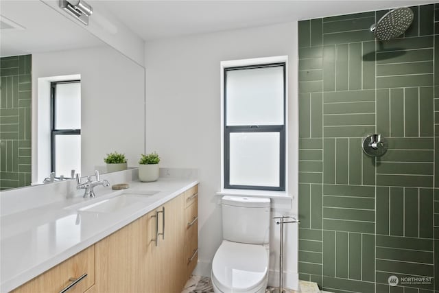 bathroom featuring vanity, tiled shower, and toilet