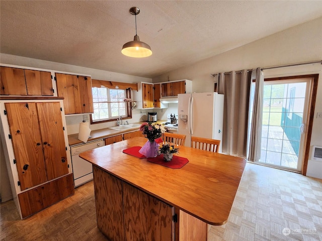 kitchen featuring vaulted ceiling, decorative light fixtures, sink, white appliances, and a textured ceiling