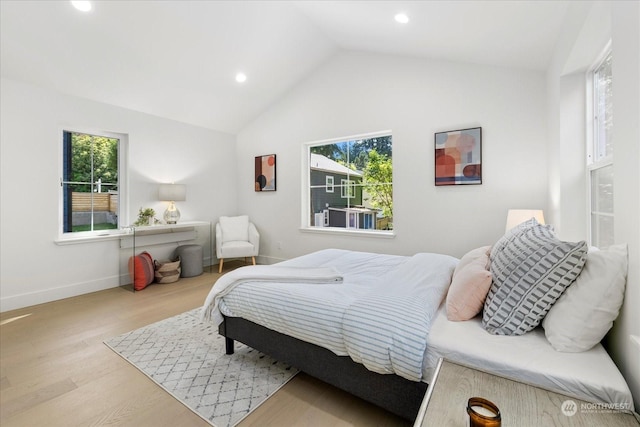 bedroom featuring lofted ceiling, multiple windows, and light hardwood / wood-style flooring