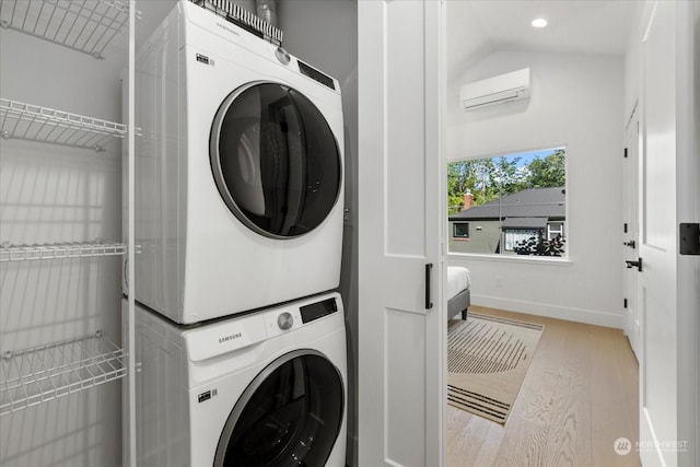 clothes washing area featuring stacked washer and dryer, light hardwood / wood-style flooring, and an AC wall unit