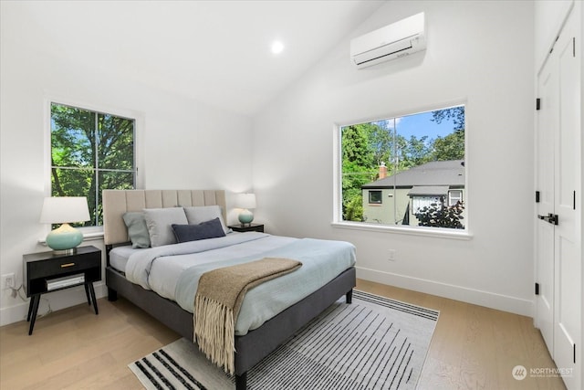 bedroom with light hardwood / wood-style floors, vaulted ceiling, and an AC wall unit