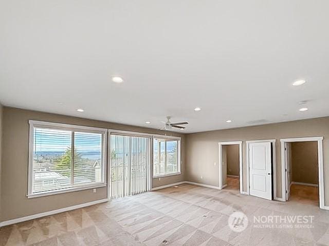 empty room featuring ceiling fan and light colored carpet