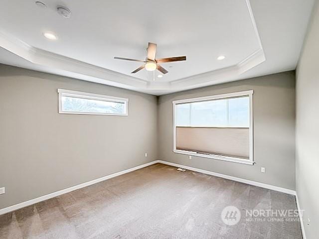 carpeted empty room featuring ceiling fan and a raised ceiling