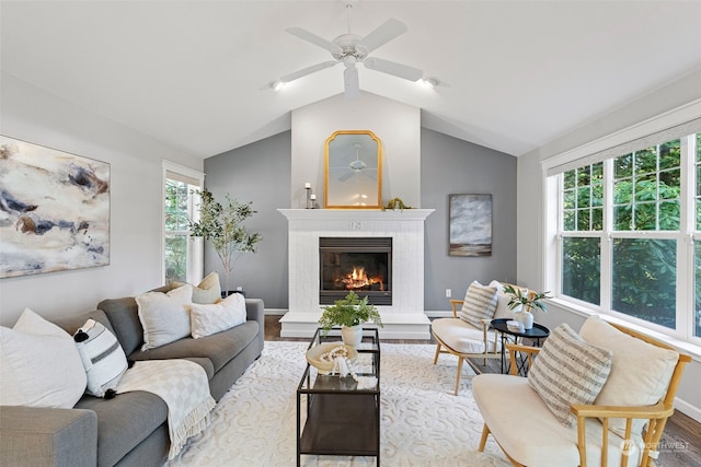 living room with a brick fireplace, light hardwood / wood-style flooring, plenty of natural light, and vaulted ceiling