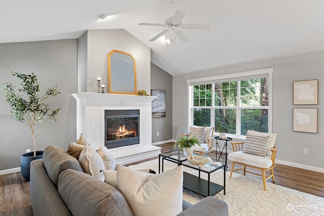 living room with a tiled fireplace, lofted ceiling, ceiling fan, and wood-type flooring