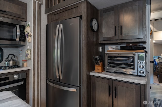 kitchen featuring dark brown cabinetry, stainless steel appliances, and decorative backsplash