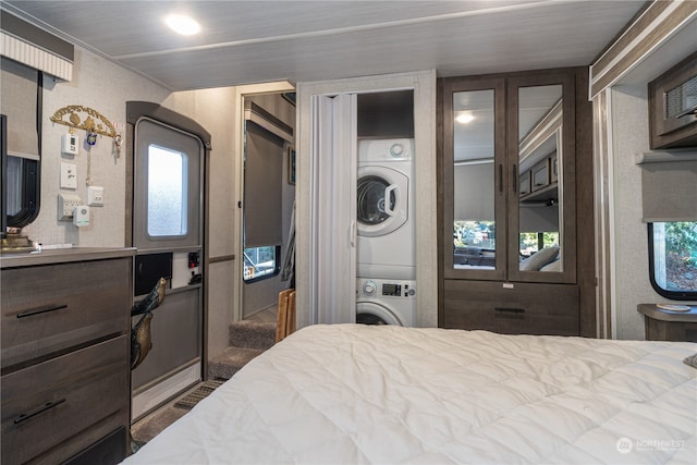 bedroom featuring stacked washer / dryer