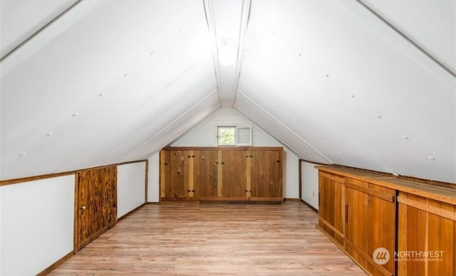 additional living space with lofted ceiling and light hardwood / wood-style flooring