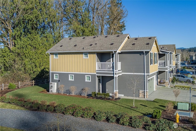 back of property featuring a garage, a lawn, and a balcony