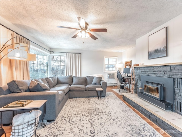 living room featuring a stone fireplace, wood-type flooring, and a healthy amount of sunlight