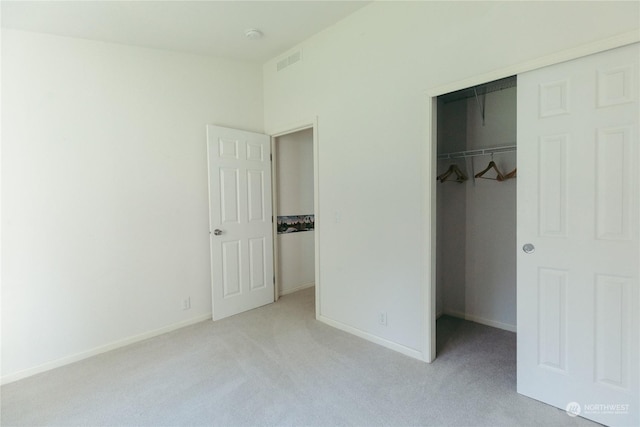 unfurnished bedroom with light colored carpet, a spacious closet, and a closet