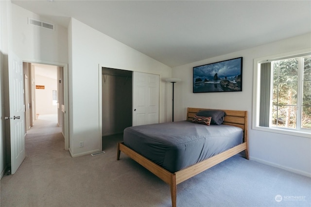 bedroom with light colored carpet, lofted ceiling, and a closet