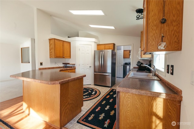 kitchen featuring lofted ceiling, sink, stainless steel fridge, a breakfast bar area, and kitchen peninsula