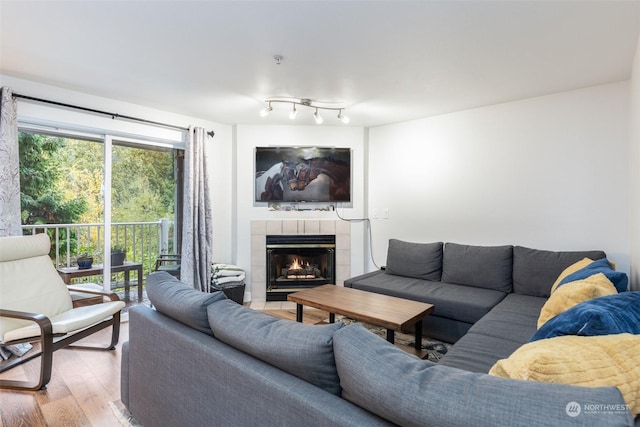 living room featuring a tiled fireplace and wood-type flooring