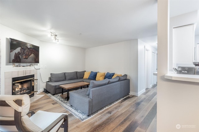 living room featuring a tile fireplace and hardwood / wood-style floors