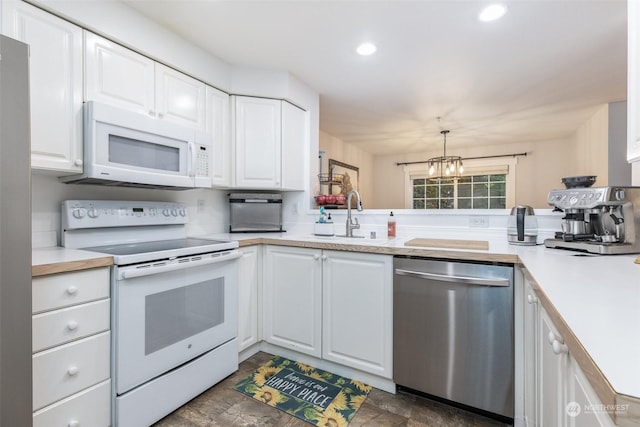 kitchen featuring white appliances, sink, hanging light fixtures, and white cabinets