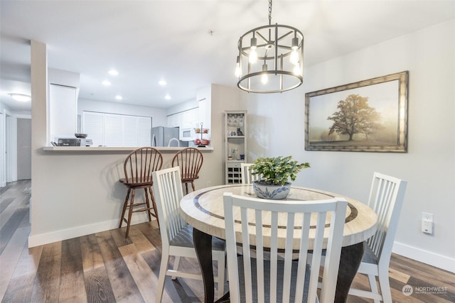 dining area with dark wood-type flooring and a chandelier