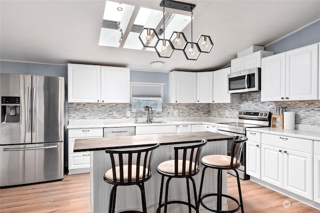 kitchen featuring sink, white cabinets, a center island, stainless steel appliances, and crown molding