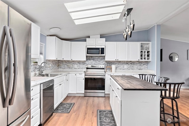 kitchen with lofted ceiling, stainless steel appliances, a center island, and white cabinets