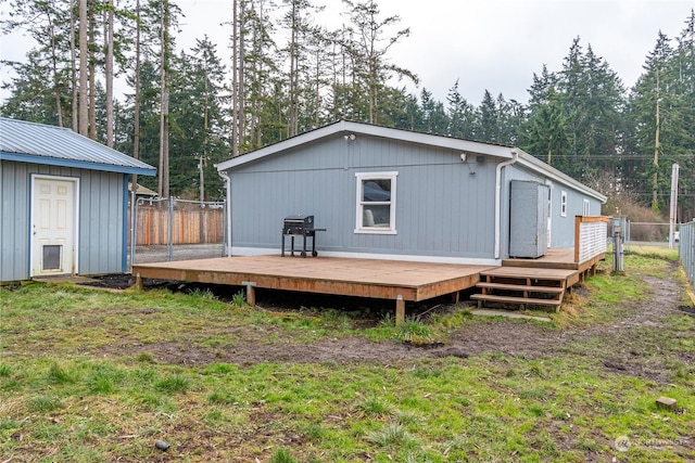 back of property featuring a wooden deck and a lawn