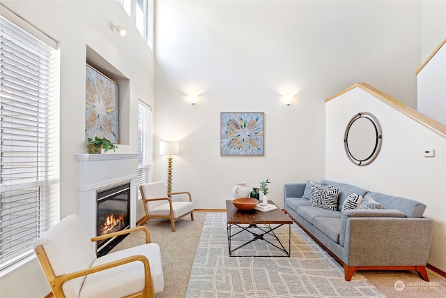 carpeted living room featuring a towering ceiling