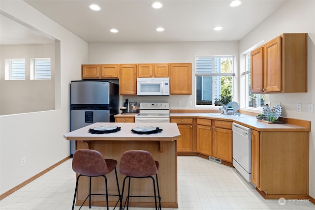 kitchen featuring sink, white appliances, a kitchen breakfast bar, and a center island