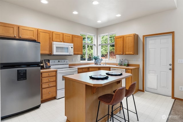 kitchen featuring white appliances, a breakfast bar, sink, and a kitchen island