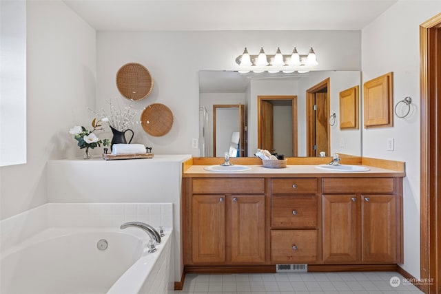 bathroom with vanity, tile patterned flooring, and tiled tub