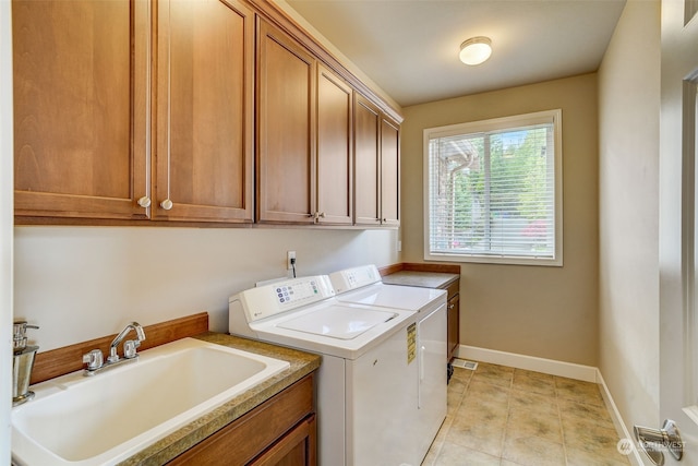 clothes washing area with sink, cabinets, washing machine and clothes dryer, and light tile patterned flooring