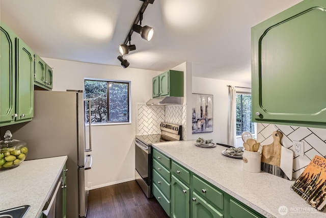 kitchen with stainless steel appliances, green cabinets, and range hood