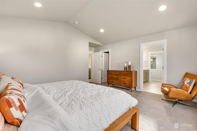 bedroom featuring lofted ceiling, light carpet, and ensuite bathroom