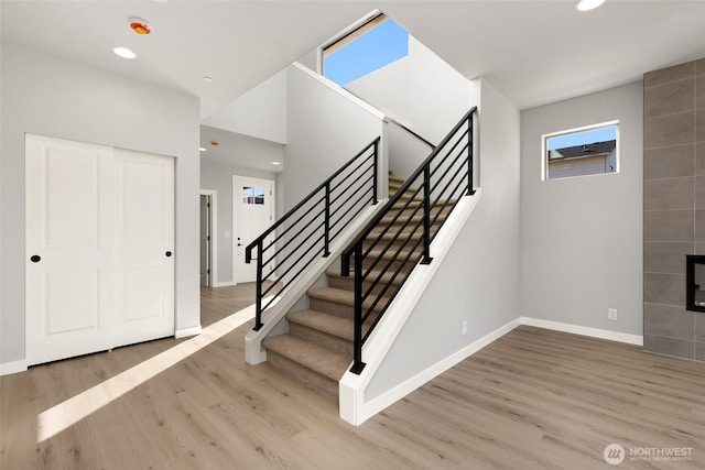 stairs featuring recessed lighting, a tile fireplace, baseboards, and wood finished floors