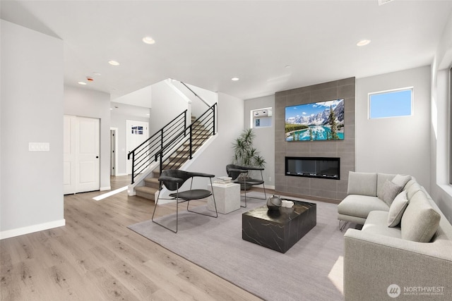 living area with wood finished floors, recessed lighting, baseboards, stairs, and a tile fireplace