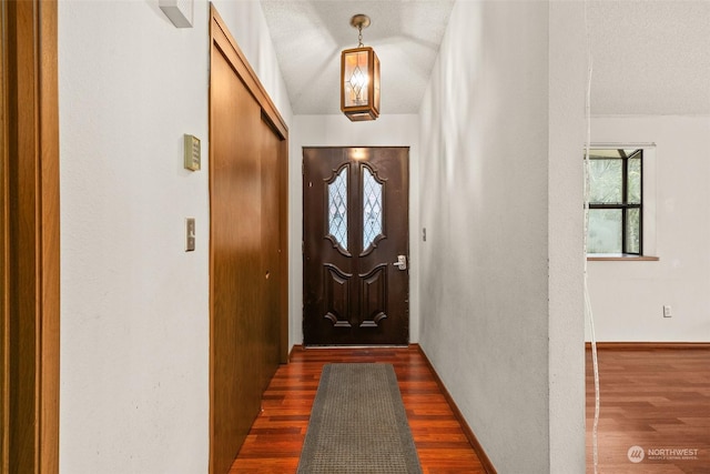 doorway to outside with dark wood-type flooring and a textured ceiling