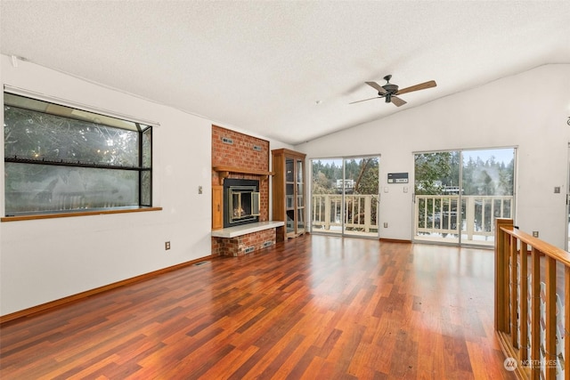 unfurnished living room featuring a brick fireplace, hardwood / wood-style flooring, vaulted ceiling, and a textured ceiling