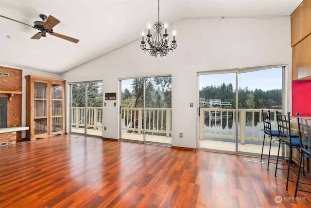 unfurnished living room featuring hardwood / wood-style floors, ceiling fan with notable chandelier, high vaulted ceiling, and a water view