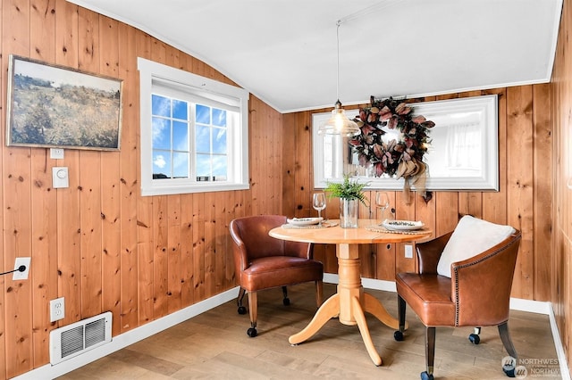 dining space featuring hardwood / wood-style flooring, vaulted ceiling, and wood walls