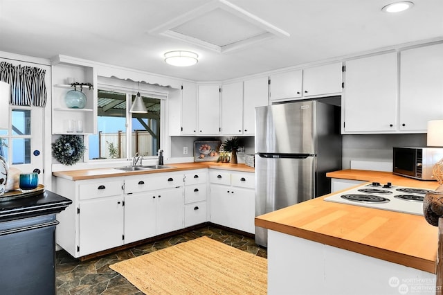 kitchen with white electric cooktop, butcher block countertops, sink, white cabinets, and stainless steel fridge