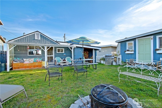 back of house featuring a yard and an outdoor fire pit