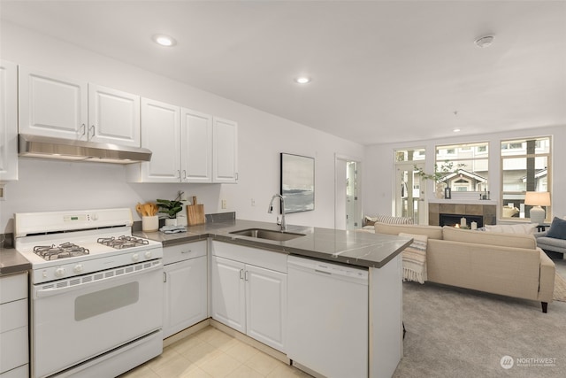 kitchen featuring white cabinetry, white appliances, a fireplace, and kitchen peninsula