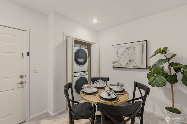 dining area featuring stacked washer and dryer and light colored carpet